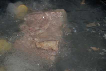 烧一锅水，投入姜块、葱节和料酒，将四四方方的带皮野猪肉放进去煮熟.jpg